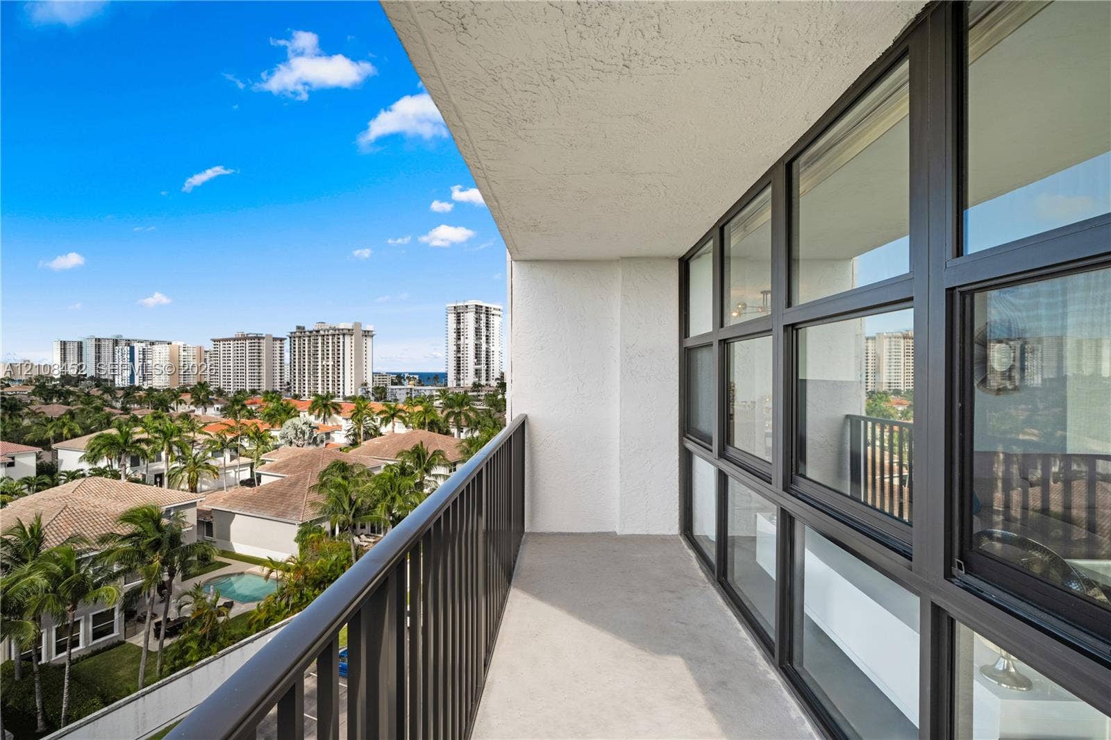 1000 Parkview Drive, #809, Hallandale Beach, FL 33009 Covered balcony featuring metal railing, concrete flooring, and extensive glass window wall with dark framing