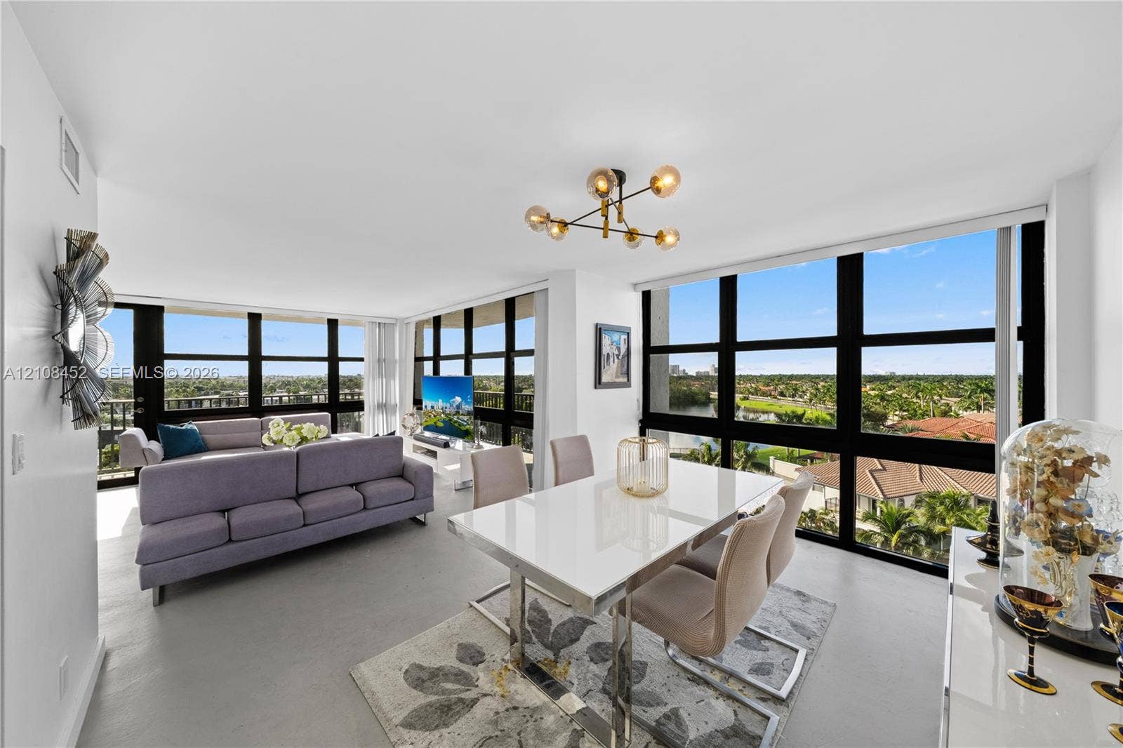 1000 Parkview Drive, #809, Hallandale Beach, FL 33009 Open-concept living space featuring floor-to-ceiling windows, uniform light-toned flooring, and a multi-arm geometric ceiling fixture