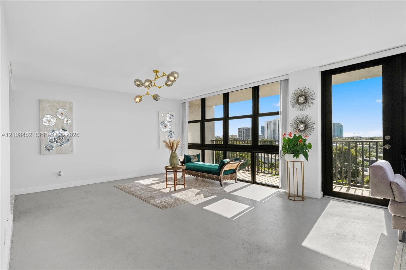 1000 Parkview Drive, #809, Hallandale Beach, FL 33009 Open-concept interior featuring floor-to-ceiling windows, polished concrete flooring, a multi-arm modern light fixture, and a private balcony access door
