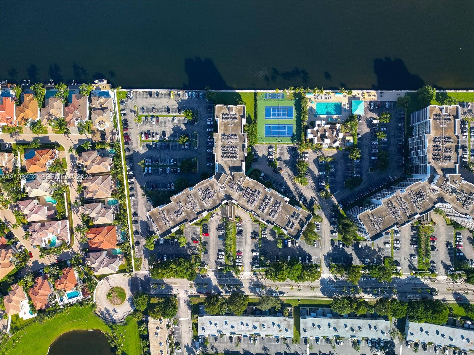 1000 Parkview Drive, #809, Hallandale Beach, FL 33009 Aerial perspective of a multi-unit residential property featuring waterfront access, two tennis courts, and a swimming pool