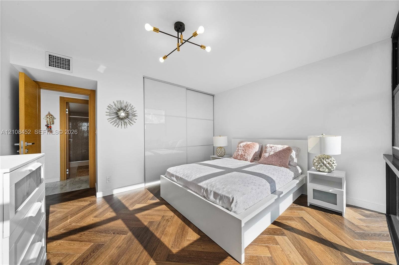 1000 Parkview Drive, #809, Hallandale Beach, FL 33009 Herringbone wood-finish flooring, floor-to-ceiling built-in gloss cabinetry, and a multi-arm geometric light fixture with matte black and brass finishes