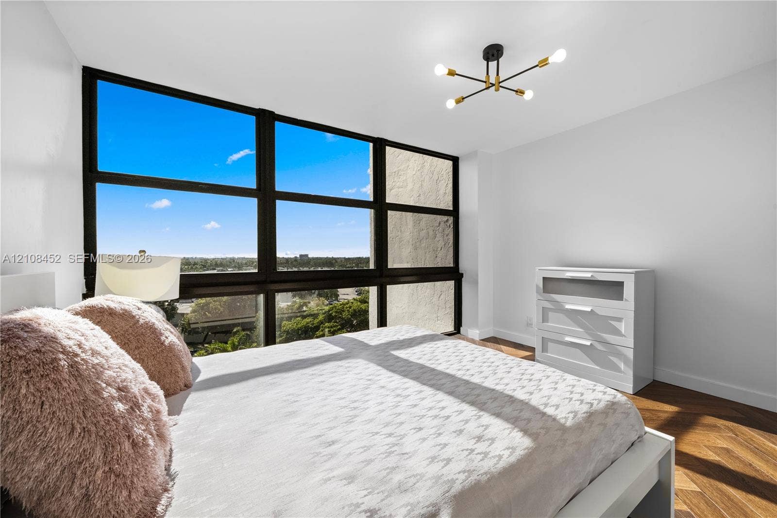1000 Parkview Drive, #809, Hallandale Beach, FL 33009 Floor-to-ceiling windows with black frames, wood-finish herringbone flooring, and a multi-arm sputnik-style ceiling light fixture