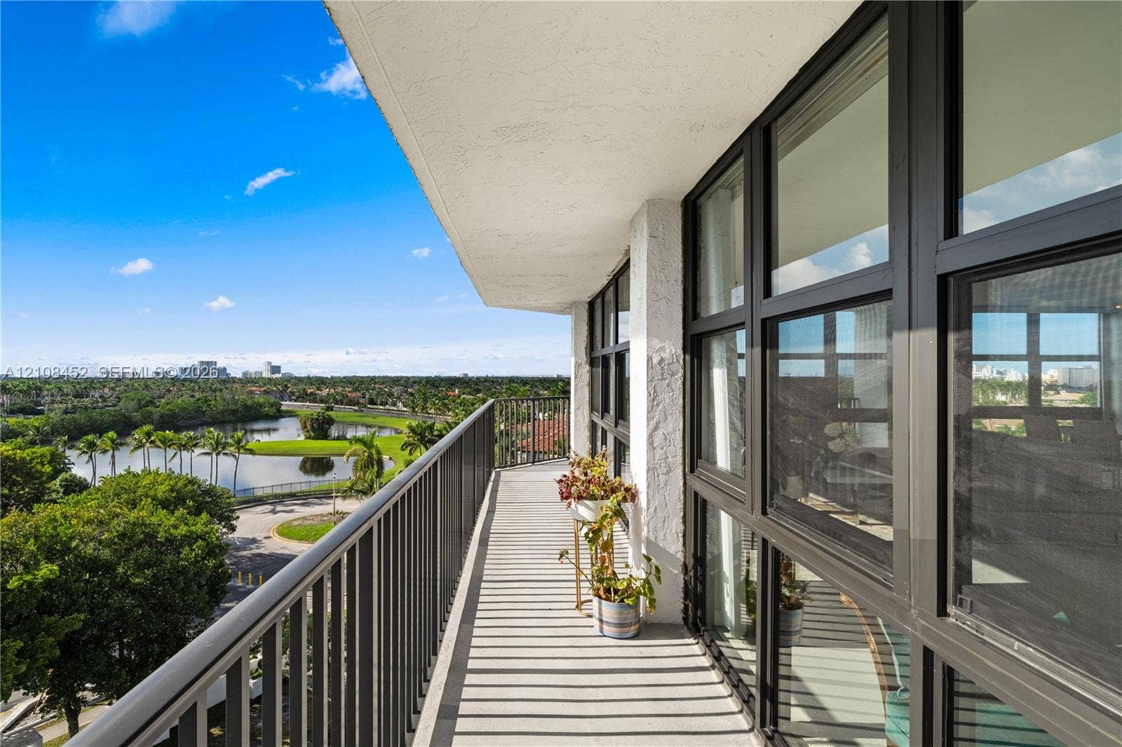 1000 Parkview Drive, #809, Hallandale Beach, FL 33009 Covered balcony featuring black metal railings, floor-to-ceiling windows with dark framing, and textured exterior wall finish