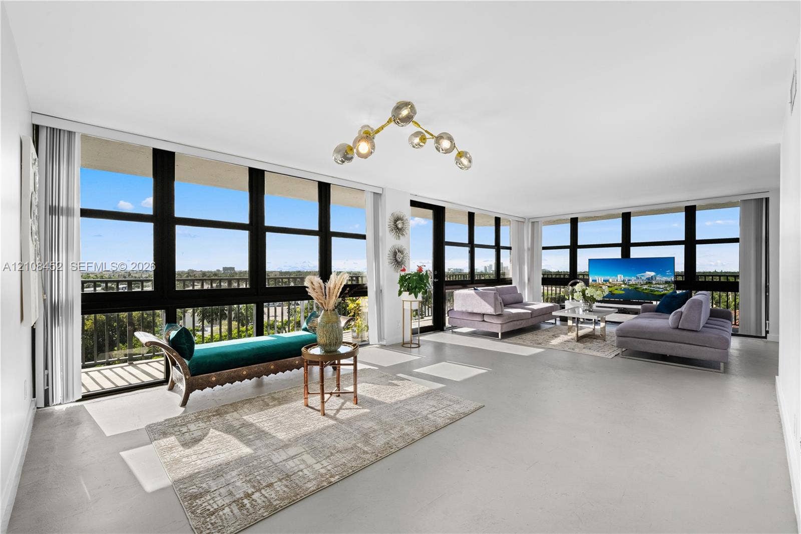 1000 Parkview Drive, #809, Hallandale Beach, FL 33009 Expansive open-concept room featuring floor-to-ceiling black-framed windows, neutral polished flooring, and a multi-globe architectural chandelier