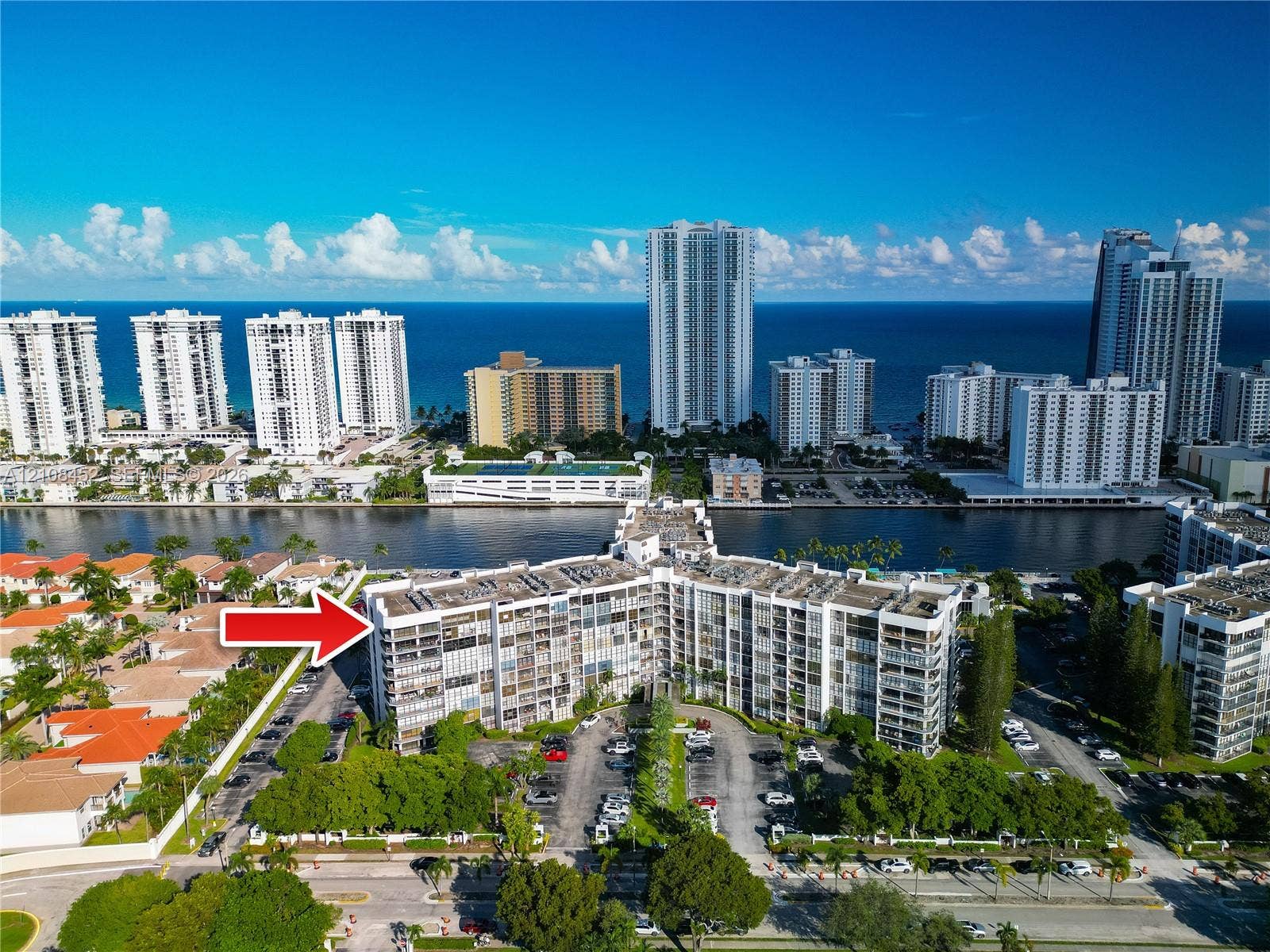 1000 Parkview Drive, #809, Hallandale Beach, FL 33009 Mid-rise multi-story residential building featuring exterior balconies, landscaped grounds, surface parking, and a waterfront location