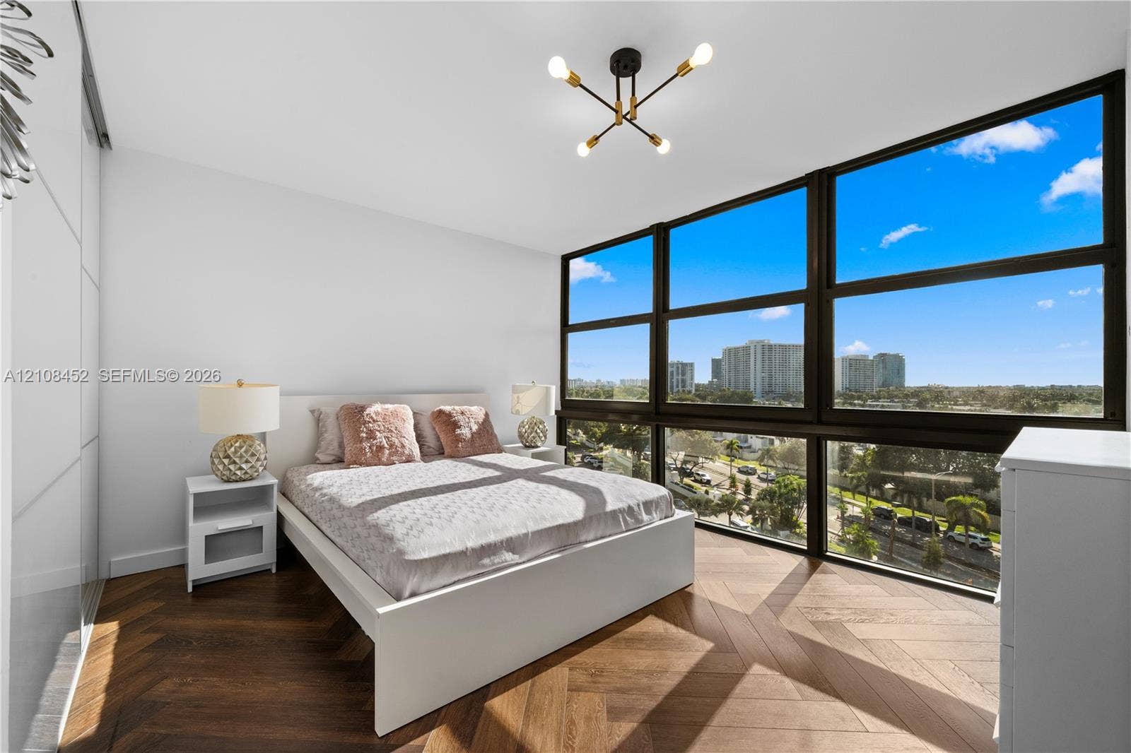1000 Parkview Drive, #809, Hallandale Beach, FL 33009 Floor-to-ceiling windows, chevron-patterned wood-finish flooring, built-in panel-front wardrobe, and a multi-arm geometric ceiling fixture