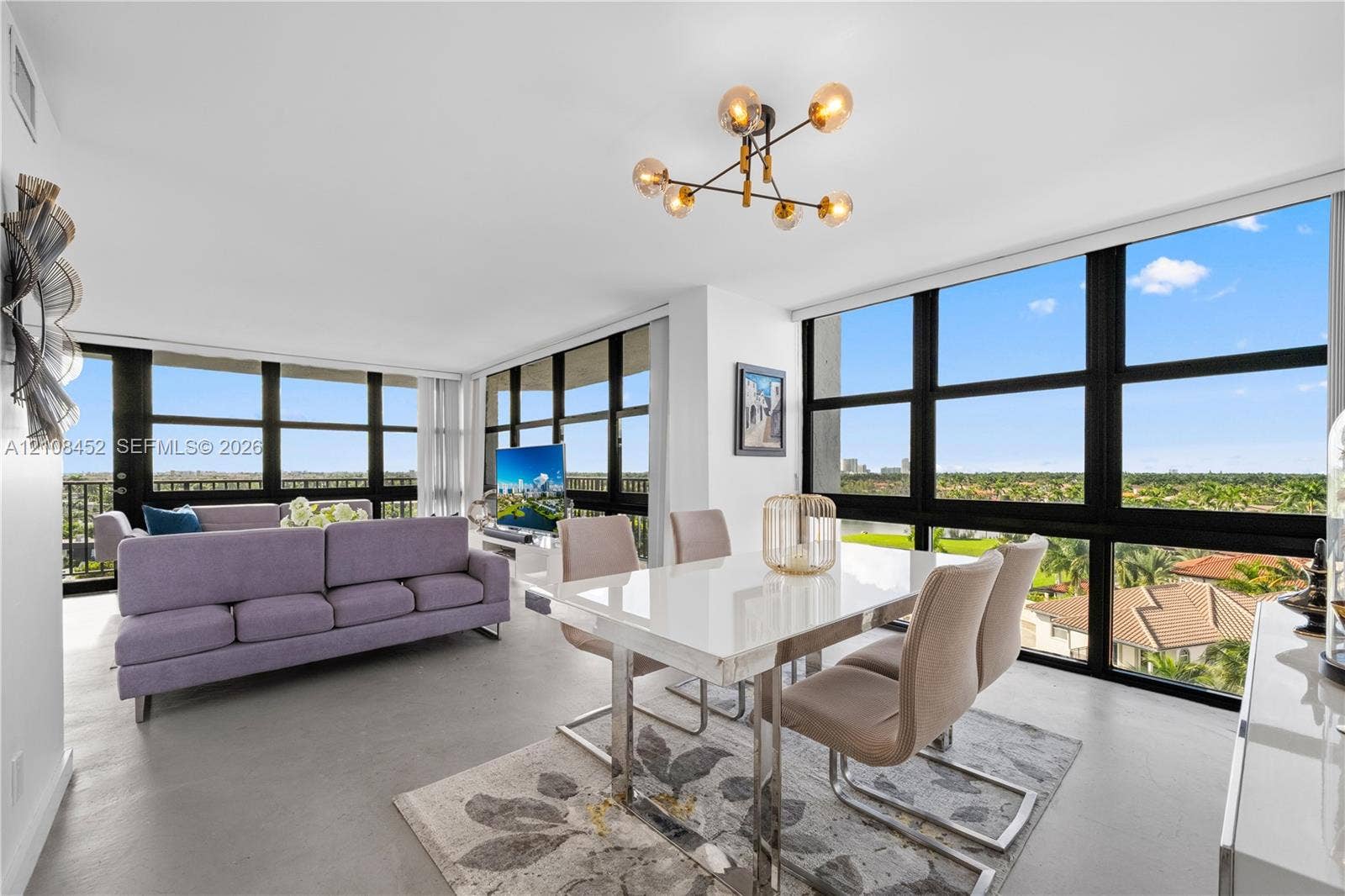 1000 Parkview Drive, #809, Hallandale Beach, FL 33009 Floor-to-ceiling windows with black framing, exposed-bulb geometric chandelier, and polished concrete flooring