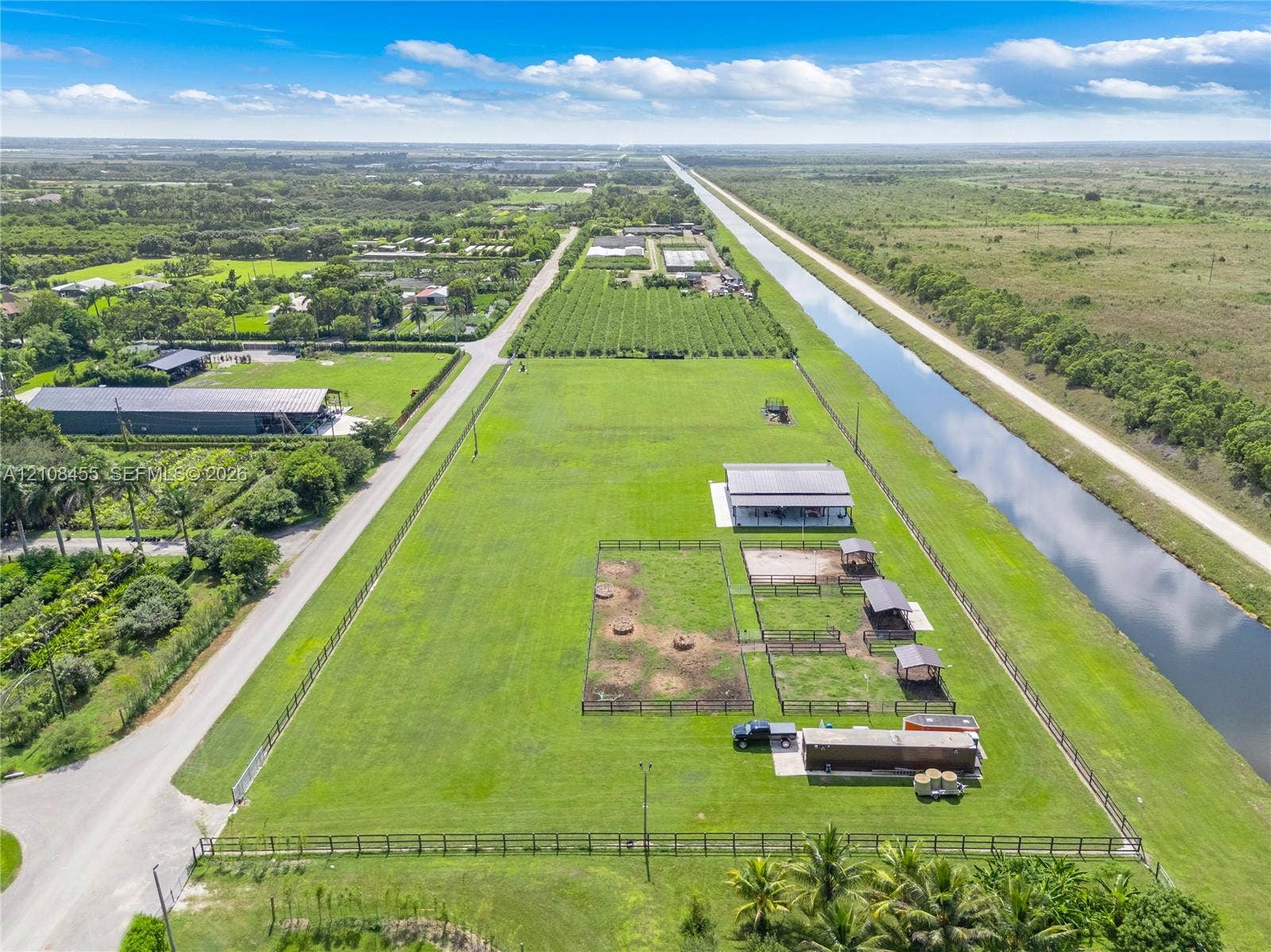 Extensive acreage featuring perimeter fencing, multiple outdoor animal enclosures, covered structures, and frontage along a waterway