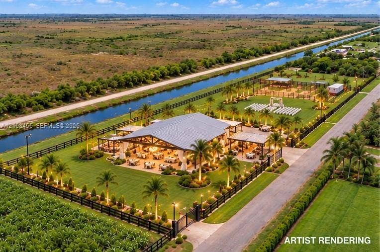 Expansive grounds featuring a metal-roof structure, manicured lawns, mature palm landscaping, and perimeter fencing