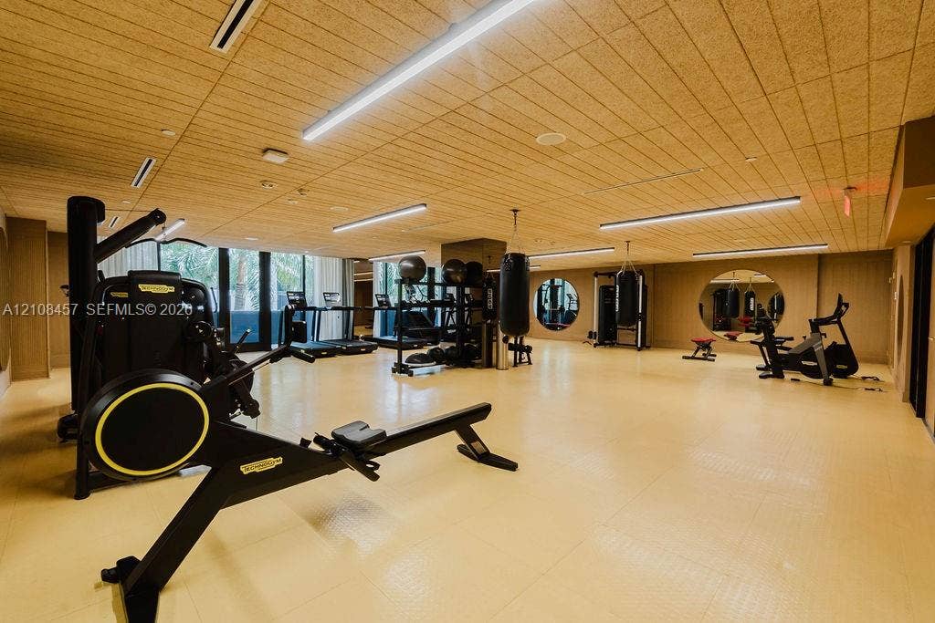 90 NE 32nd Street, #511, Miami, FL 33127 Spacious fitness room featuring wood-slat ceiling, recessed linear lighting, circular wall mirrors, and textured resilient flooring
