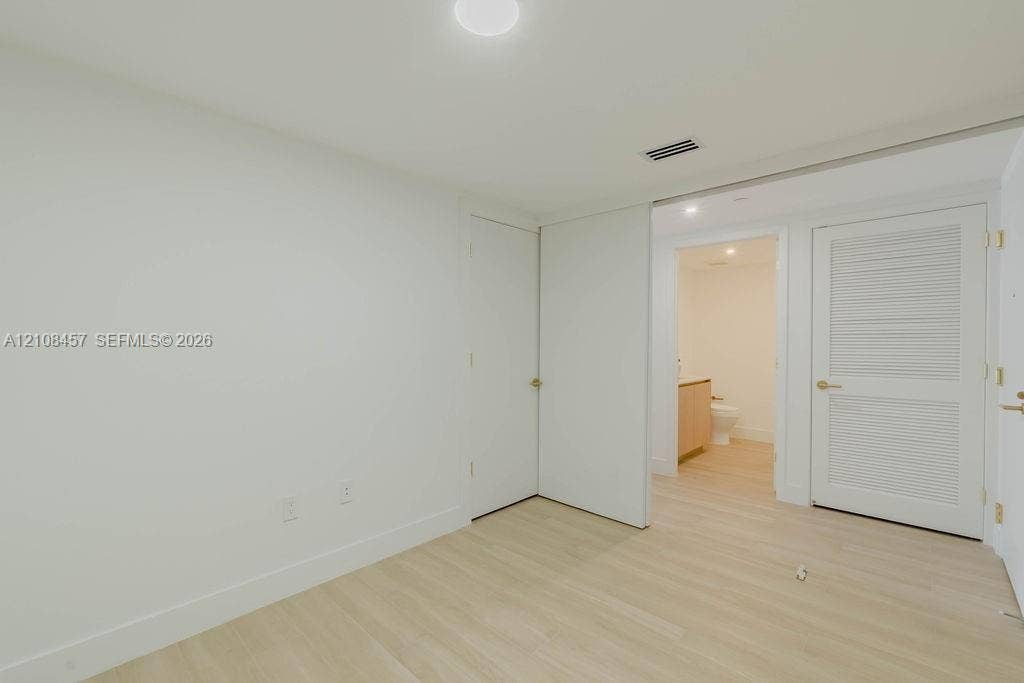 90 NE 32nd Street, #511, Miami, FL 33127 Interior space featuring wood-finish flooring, a louvered closet door, a flush-mount ceiling light fixture, and a neutral color palette