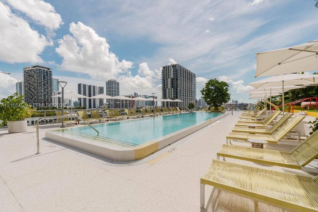 90 NE 32nd Street, #511, Miami, FL 33127 Rooftop swimming pool featuring a rectangular basin, light-colored hardscaping, integrated safety railing, and metal handrails