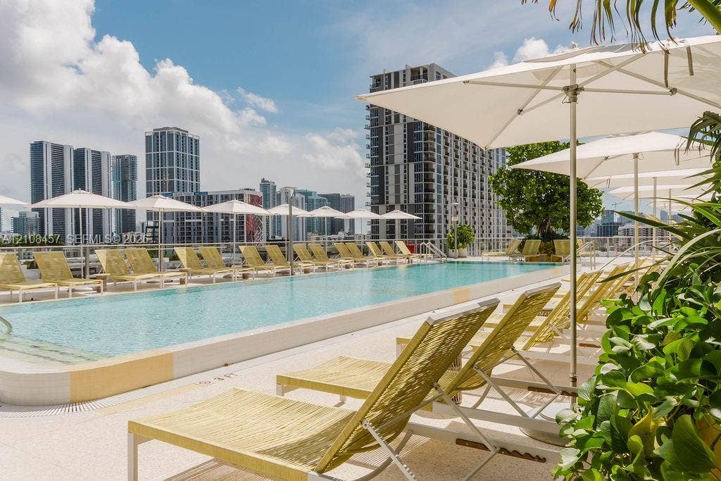 90 NE 32nd Street, #511, Miami, FL 33127 Rooftop swimming pool with a light-colored paved deck, surrounding metal railing, and integrated pool steps