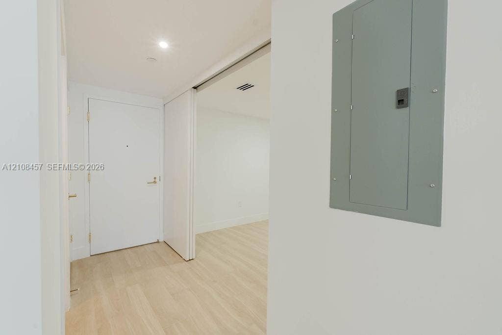 90 NE 32nd Street, #511, Miami, FL 33127 Interior entry featuring light-toned wood-finish flooring, recessed ceiling lighting, a solid-core door with metallic hardware, and an integrated electrical service panel