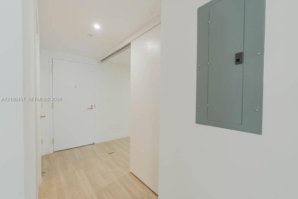 90 NE 32nd Street, #511, Miami, FL 33127 Interior entrance featuring light-toned wood-finish flooring, a solid core entry door with metallic hardware, recessed ceiling lighting, and a white sliding door