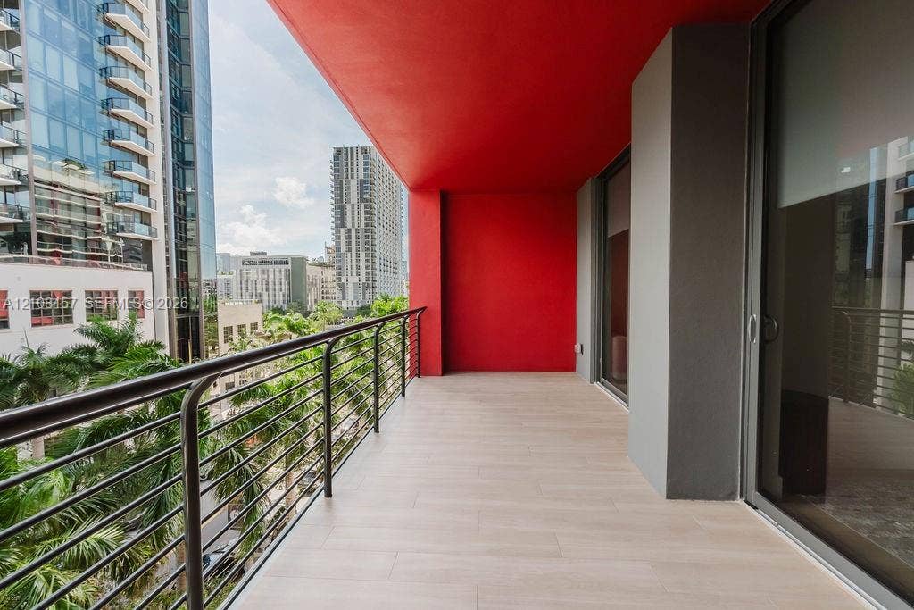 90 NE 32nd Street, #511, Miami, FL 33127 Covered balcony featuring wood-finish tile flooring, metal railing, and high-contrast red ceiling accent