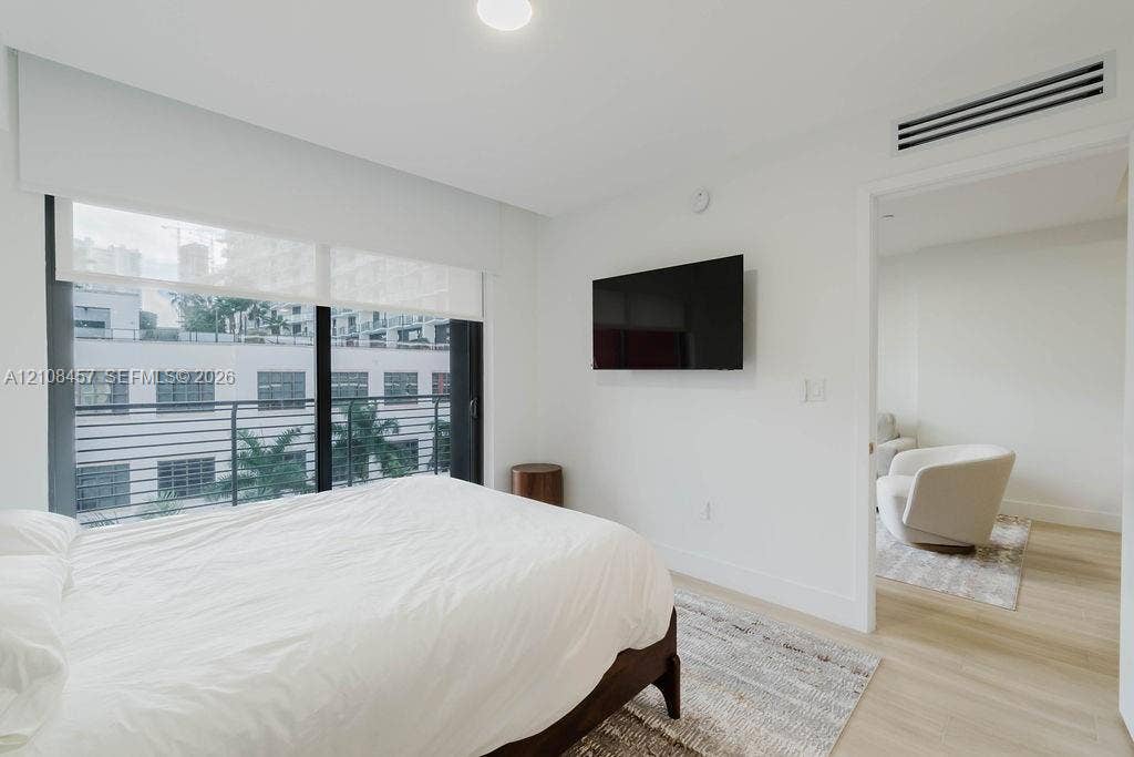90 NE 32nd Street, #511, Miami, FL 33127 Floor-to-ceiling windows featuring automated roller shades, wood-finish flooring, and a private balcony with horizontal metal railing