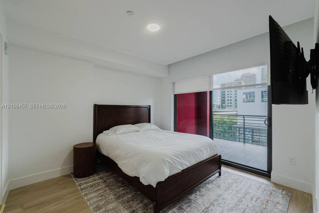 90 NE 32nd Street, #511, Miami, FL 33127 Sliding glass door opening to a private balcony with metal railing, neutral wood-finish flooring, and recessed ceiling lighting