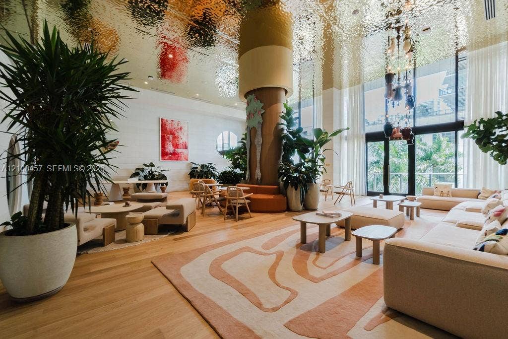 90 NE 32nd Street, #511, Miami, FL 33127 Common area featuring a textured gold-finish ceiling, floor-to-ceiling windows, wide-plank wood flooring, and a central architectural pillar