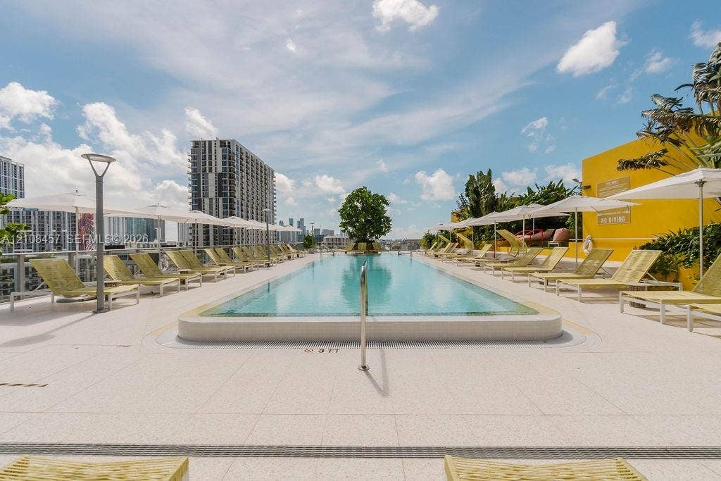 90 NE 32nd Street, #511, Miami, FL 33127 Rooftop swimming pool featuring a tiled deck, metal handrail, and integrated landscaping