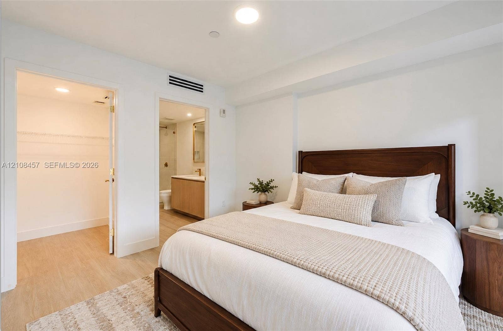 90 NE 32nd Street, #511, Miami, FL 33127 Neutral-toned wood-finish flooring, walk-in closet with built-in shelving, and bathroom featuring a light-finish wood vanity with a solid-surface countertop