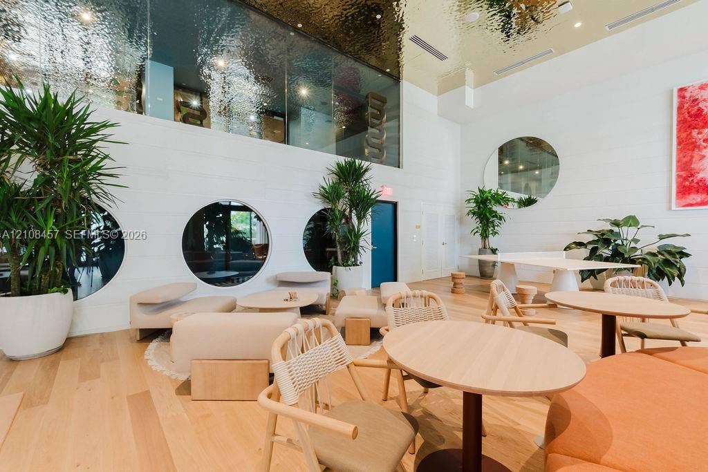 90 NE 32nd Street, #511, Miami, FL 33127 Expansive common area featuring high ceilings with a metallic finish, light wood-finish flooring, circular windows, and a large round wall mirror