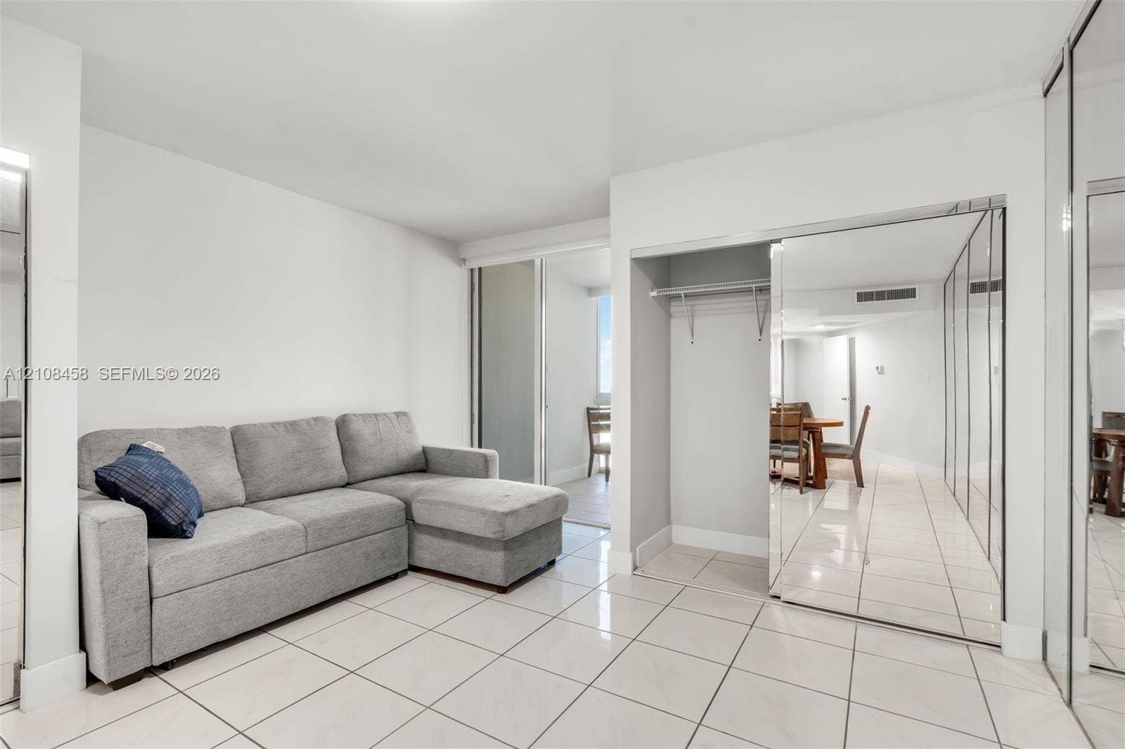Neutral-toned tile flooring, mirrored sliding closet doors, and open-concept architectural design