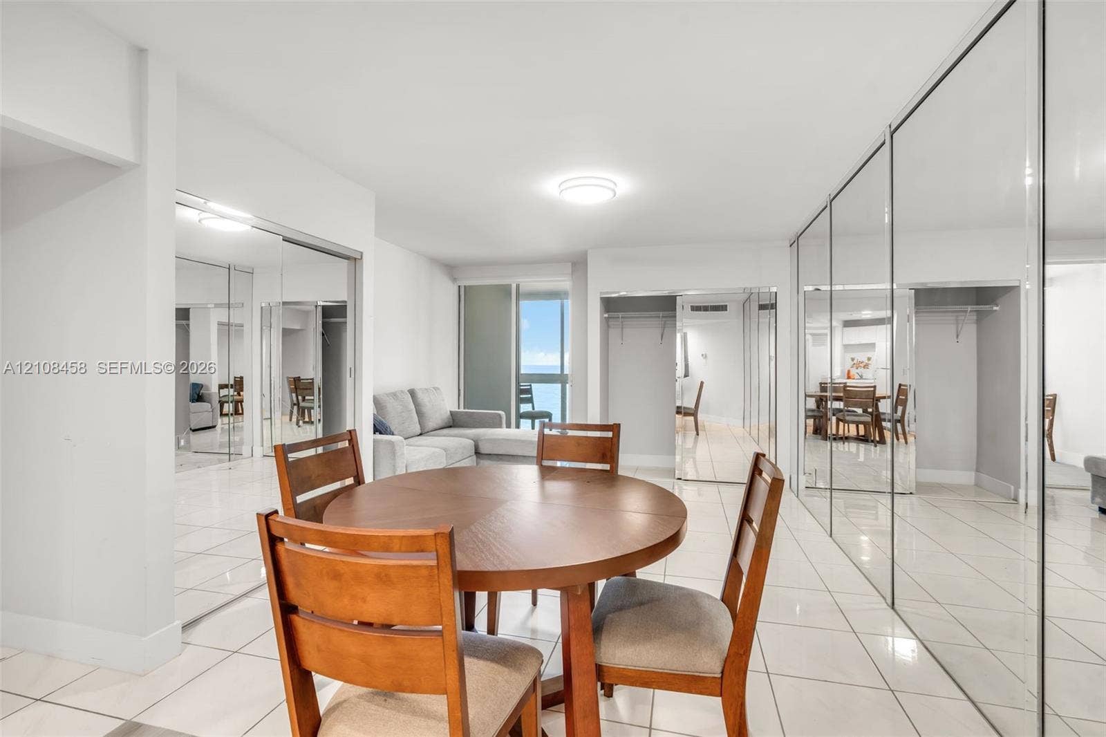 Expansive living area featuring reflective floor-to-ceiling mirrored closet doors, polished tile flooring, and a sliding glass door providing external natural light