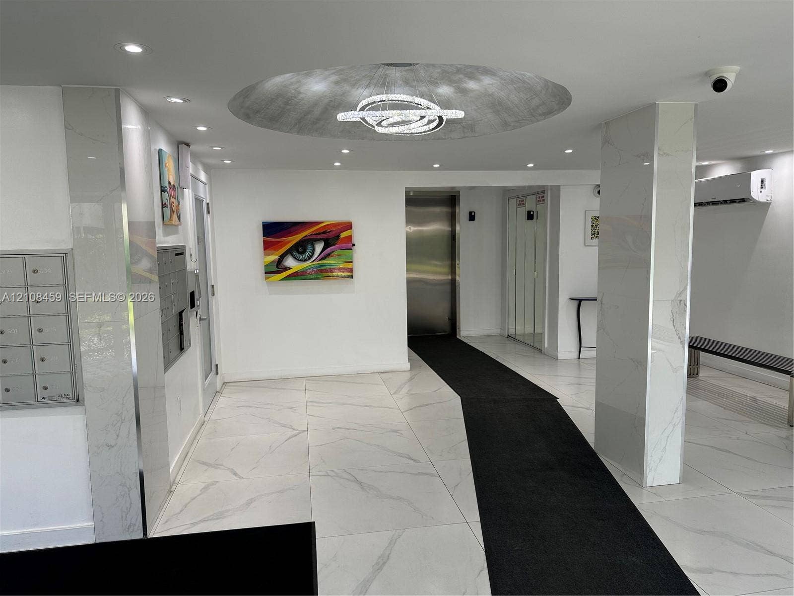 720 Collins Avenue, #206, Miami Beach, Miami Beach, FL 33139 Lobby interior featuring large-format stone-finish floor tiling, polished stone-clad columns, recessed lighting, a modern sculptural ceiling fixture, and stainless steel elevator doors