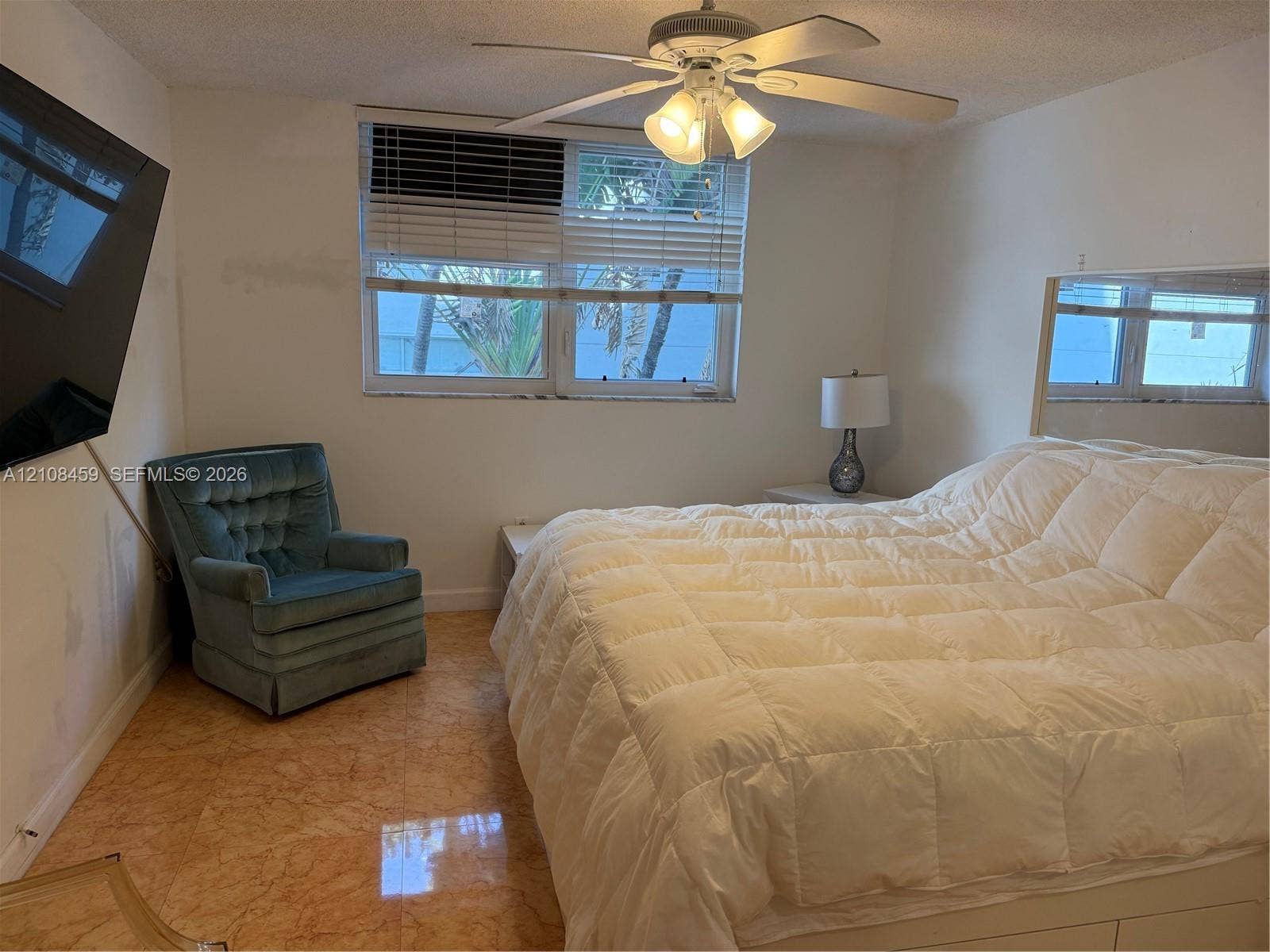 720 Collins Avenue, #206, Miami Beach, Miami Beach, FL 33139 Polished stone flooring, ceiling-mounted fan with integrated light fixture, large-format wall mirror, and window with blinds