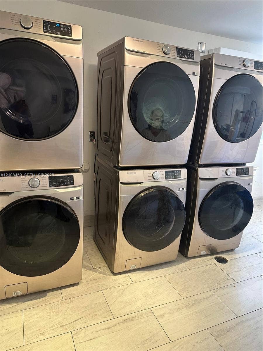 720 Collins Avenue, #206, Miami Beach, Miami Beach, FL 33139 Laundry area featuring five stacked front-load washers and dryers with metallic finishes and light-toned tile flooring