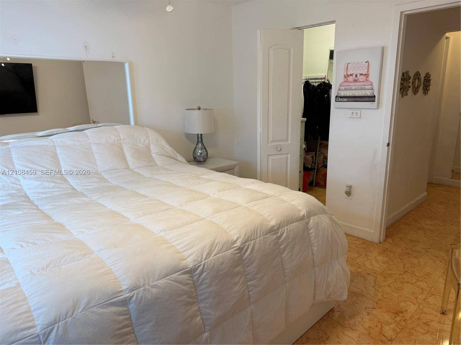 720 Collins Avenue, #206, Miami Beach, Miami Beach, FL 33139 Bedroom featuring a large wall-mounted mirror, neutral interior paint, stone-finish tile flooring, and a walk-in closet with an arched two-panel door