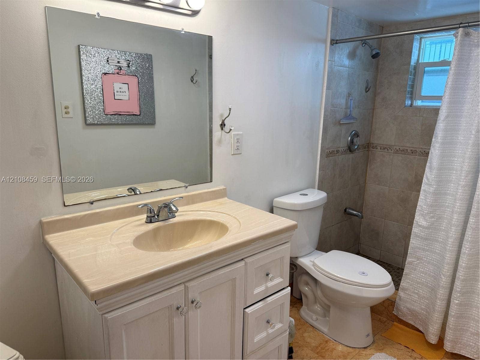720 Collins Avenue, #206, Miami Beach, Miami Beach, FL 33139 Vanity with stone-finish countertop, integrated sink, and white cabinetry, paired with a square wall-mounted mirror, ceramic tile shower surround, and chrome shower fixtures