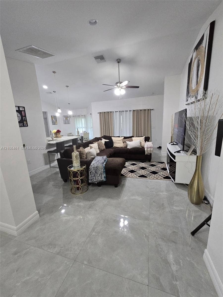 Large-format polished tile flooring, high ceilings, integrated recessed lighting, and a ceiling fan with light kit