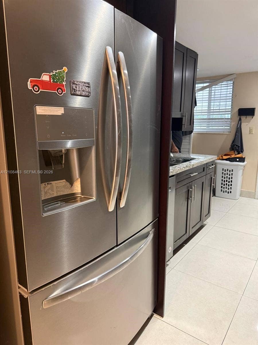 1798 W 75th Street, #1798, Hialeah, Hialeah, FL 33014 Stainless steel French door refrigerator with exterior water and ice dispenser, dark-toned cabinetry, light-toned stone-finish countertops, and tile flooring