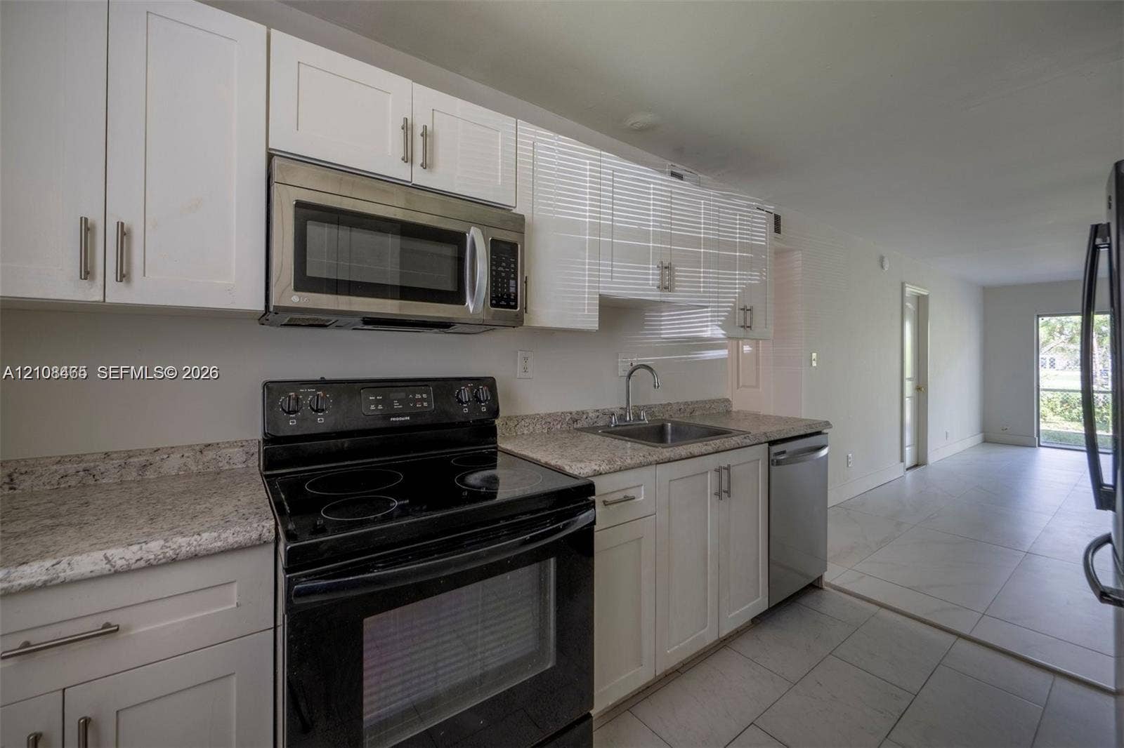 Kitchen featuring white shaker-style cabinetry, stone countertops, stainless steel microwave, black electric range, and tile flooring