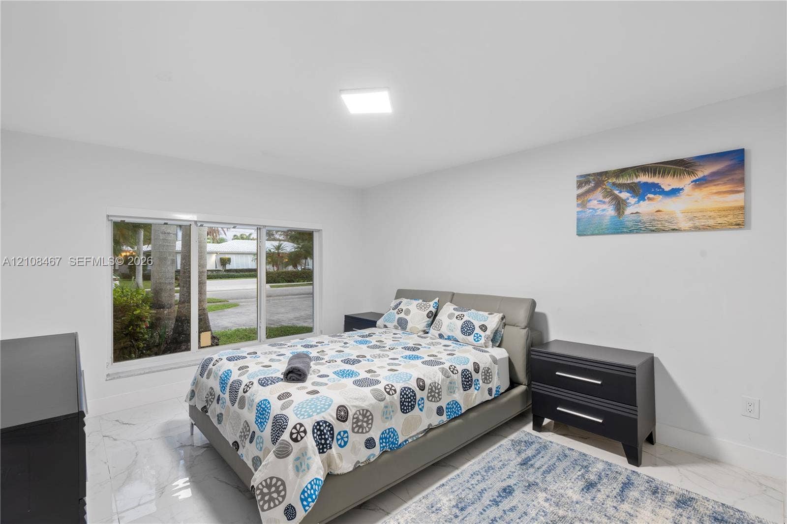 Neutral-toned interior featuring large-format tile flooring, a multi-pane picture window, and a flush-mount ceiling light fixture