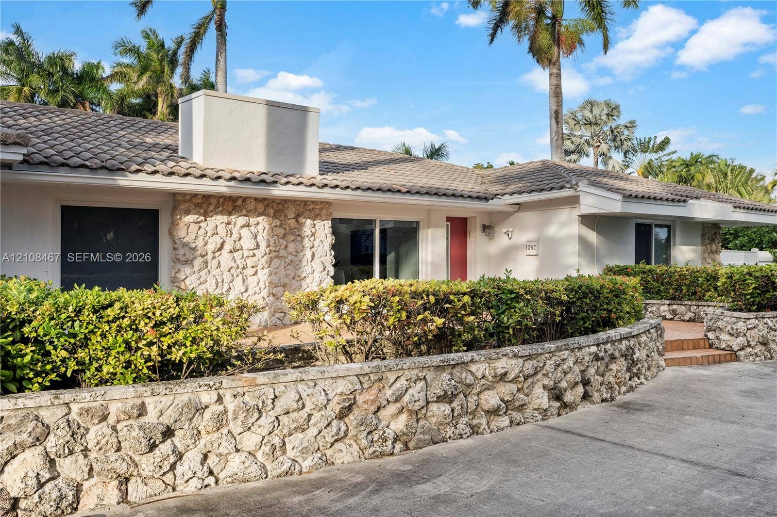 Single-story exterior featuring natural stone masonry facade and retaining walls, tiled roof, and integrated landscaping