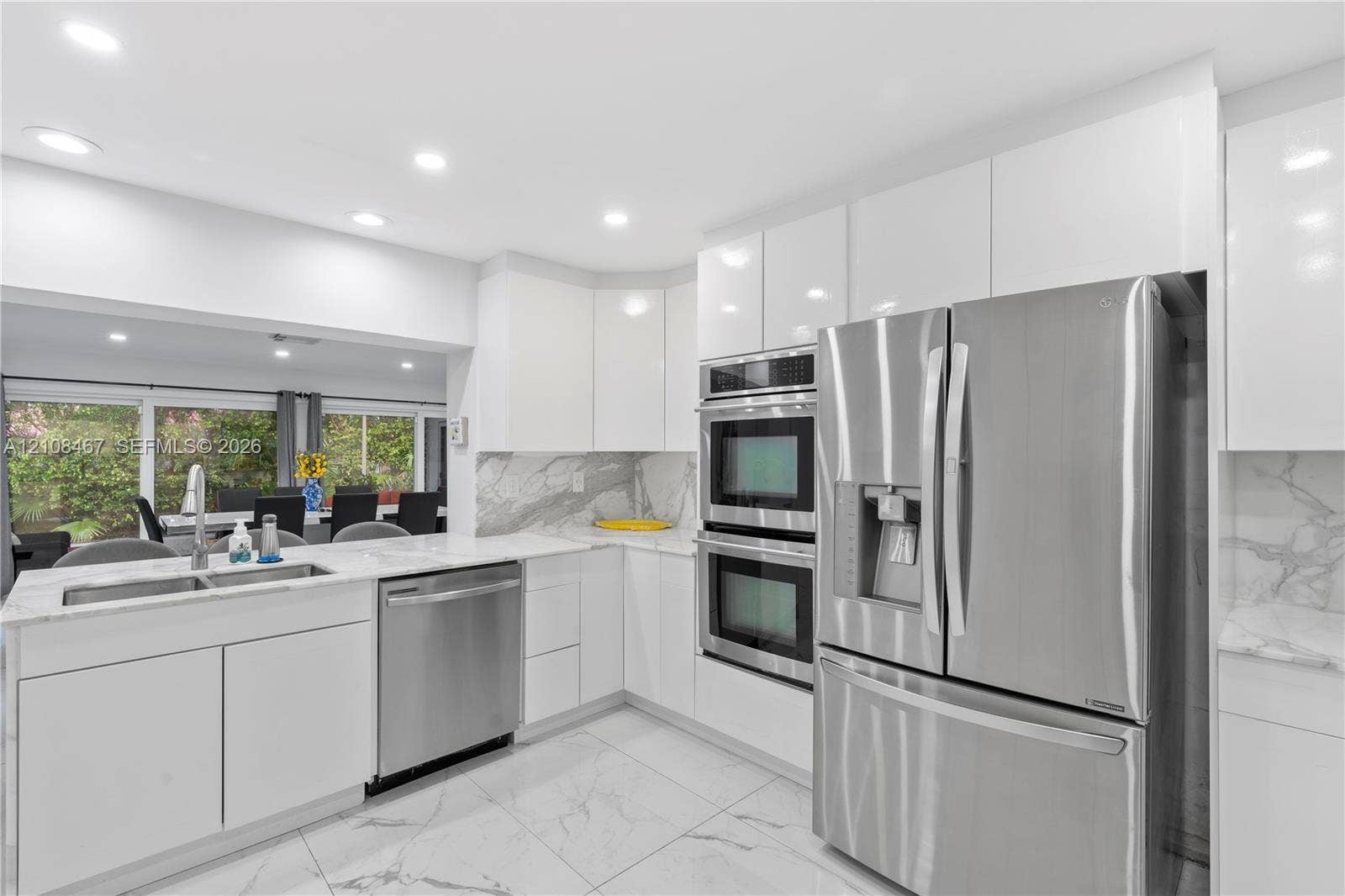 Kitchen featuring flat-panel white cabinetry, stone-surface countertops, stainless steel appliances, double wall ovens, and large-format tile flooring