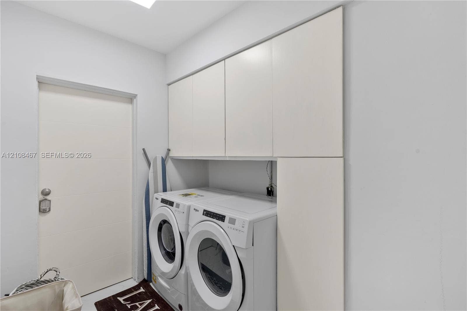 Utility room featuring white, flat-panel built-in cabinetry providing overhead and full-height vertical storage