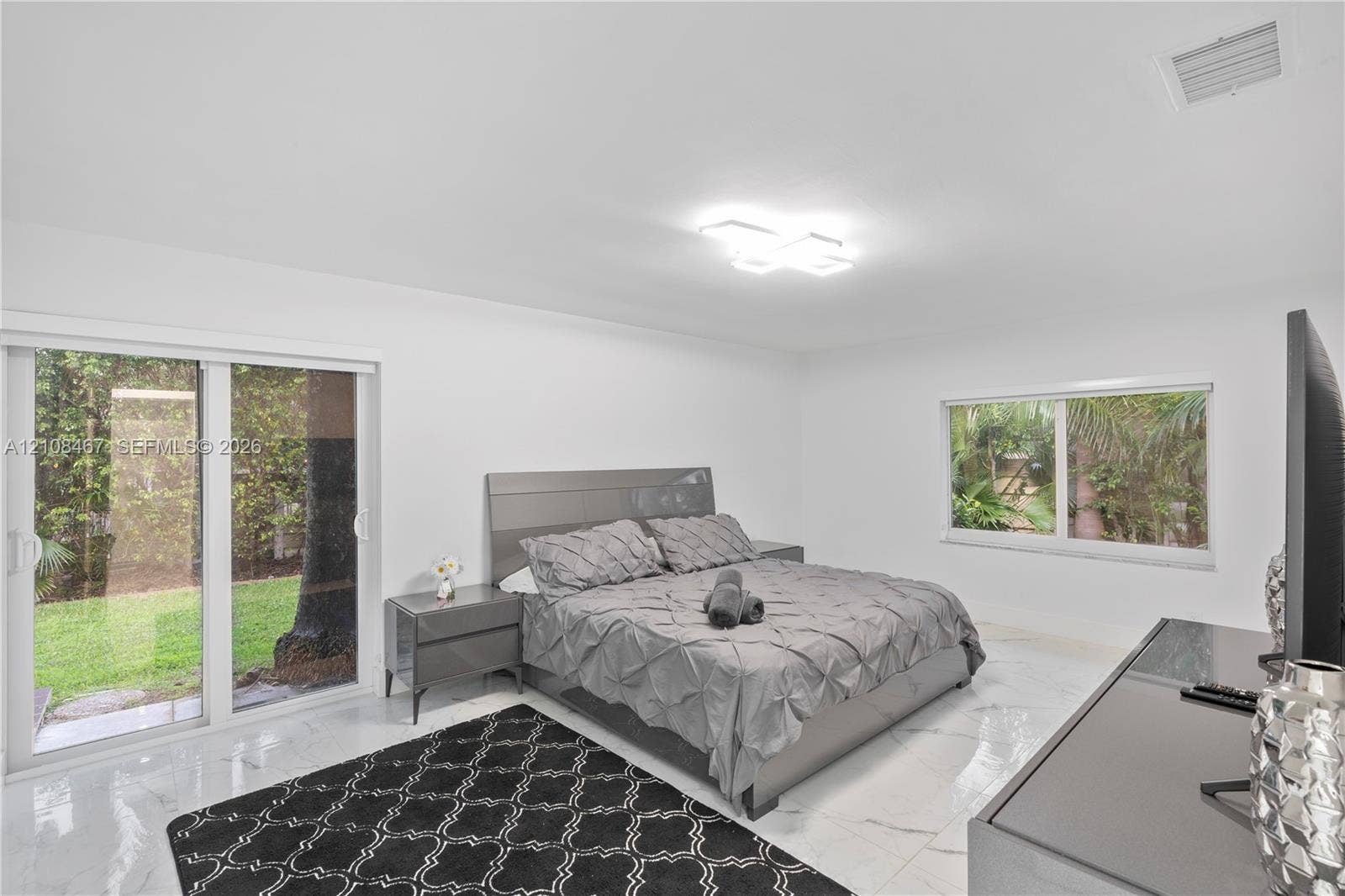 Polished stone-finish flooring, sliding glass door with exterior access, dual-pane window, and modern geometric flush-mount ceiling light fixture