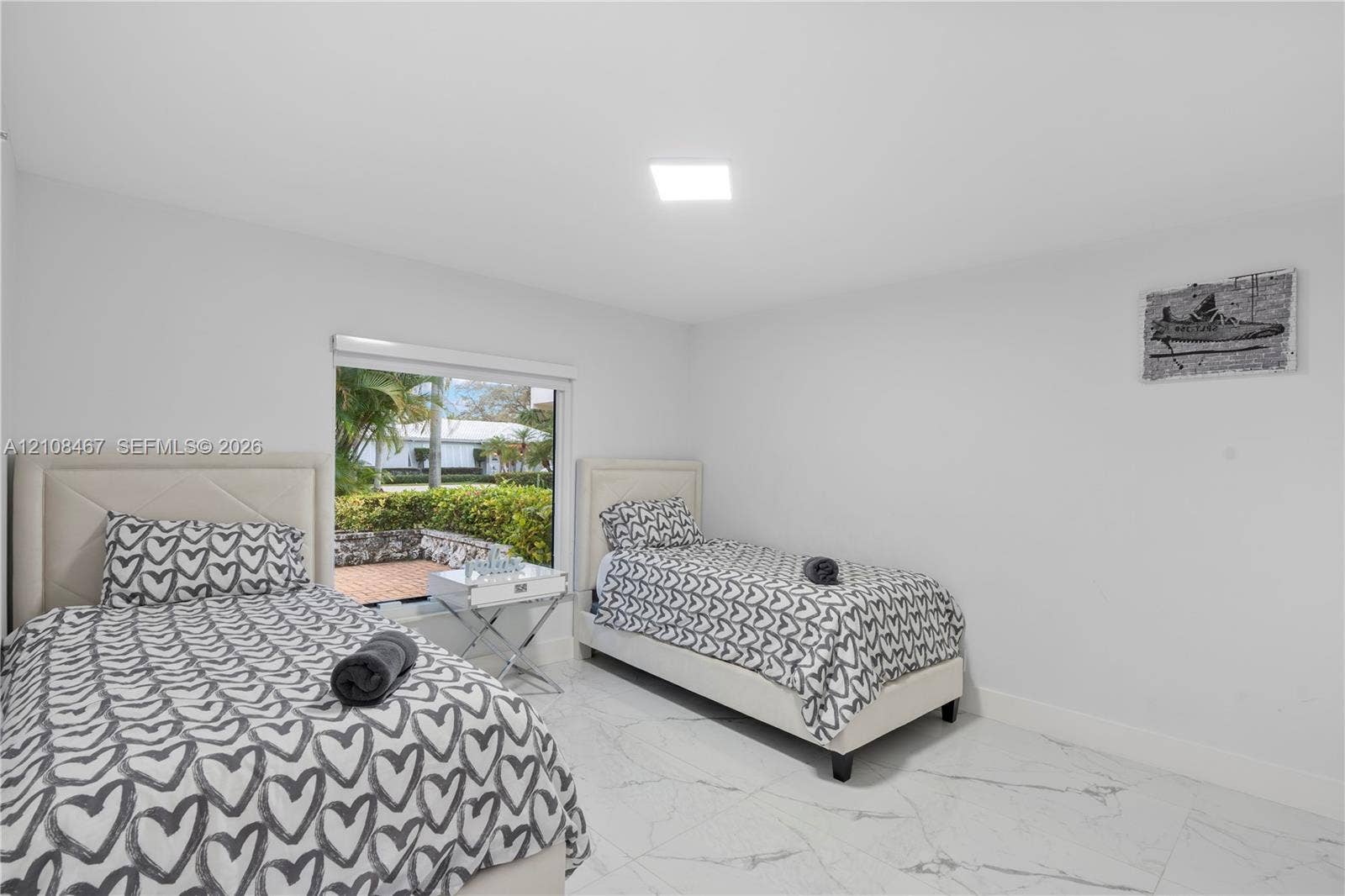 Neutral-toned room featuring large-format tile flooring and a rectangular window with exterior greenery
