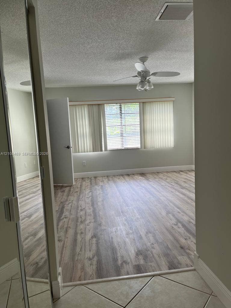 21362 Juego Circle, #33E, Boca Raton, Boca Raton, FL 33433 Room featuring wood-finish flooring, a ceiling fan with integrated lighting, and mirrored closet doors.