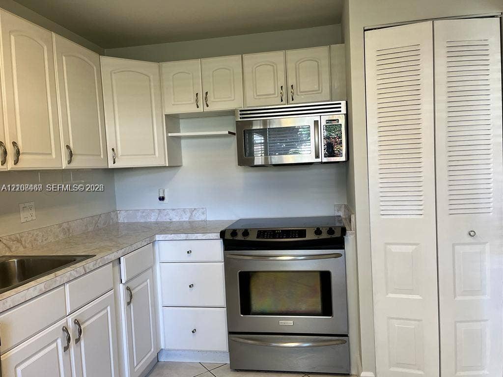 21362 Juego Circle, #33E, Boca Raton, Boca Raton, FL 33433 Kitchen featuring white cabinetry, stone-finish countertops, stainless steel appliances, and pantry for extra storage