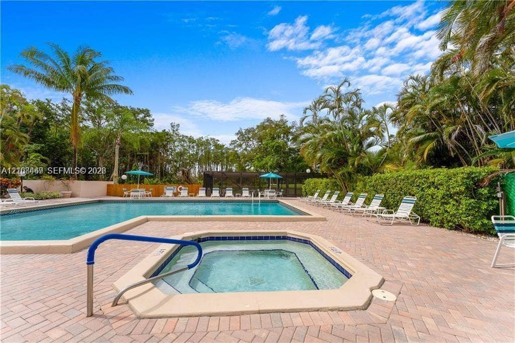 21362 Juego Circle, #33E, Boca Raton, Boca Raton, FL 33433 In-ground swimming pool and attached spa featuring a brick-paver pool deck, perimeter landscaping, and privacy fencing.
