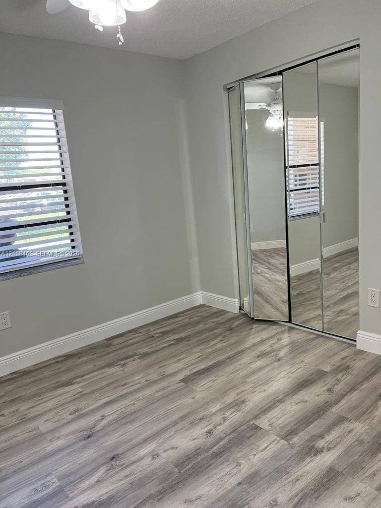 21362 Juego Circle, #33E, Boca Raton, Boca Raton, FL 33433 Wood-finish flooring, mirrored sliding closet doors, horizontal slat window blinds, and a ceiling-mounted light fixture