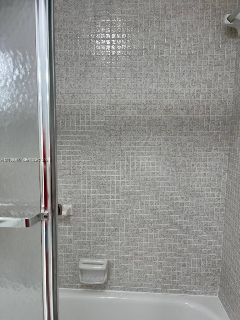 21362 Juego Circle, #33E, Boca Raton, Boca Raton, FL 33433 Bath with Tub, featuring small-format mosaic wall tiling, a built-in soap dish, and a enclosure framed glass door