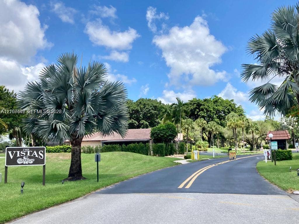 21362 Juego Circle, #33E, Boca Raton, Boca Raton, FL 33433 Paved entrance road featuring mature palm trees, manicured lawn.