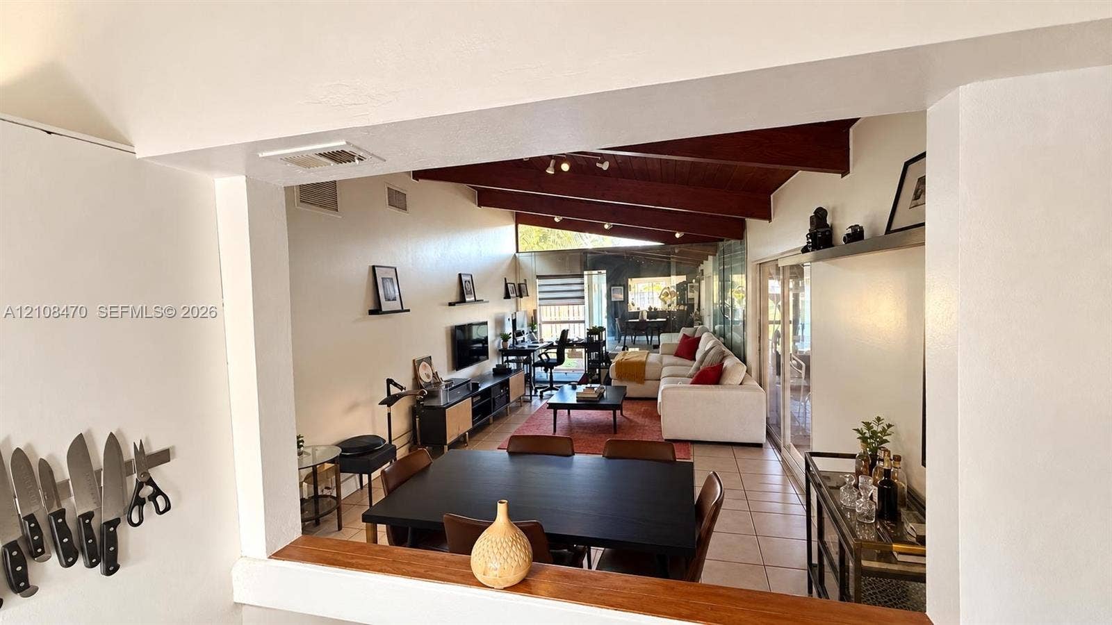 Vaulted wood-beam ceiling, open-concept floor plan, sliding glass doors, and ceramic tile flooring