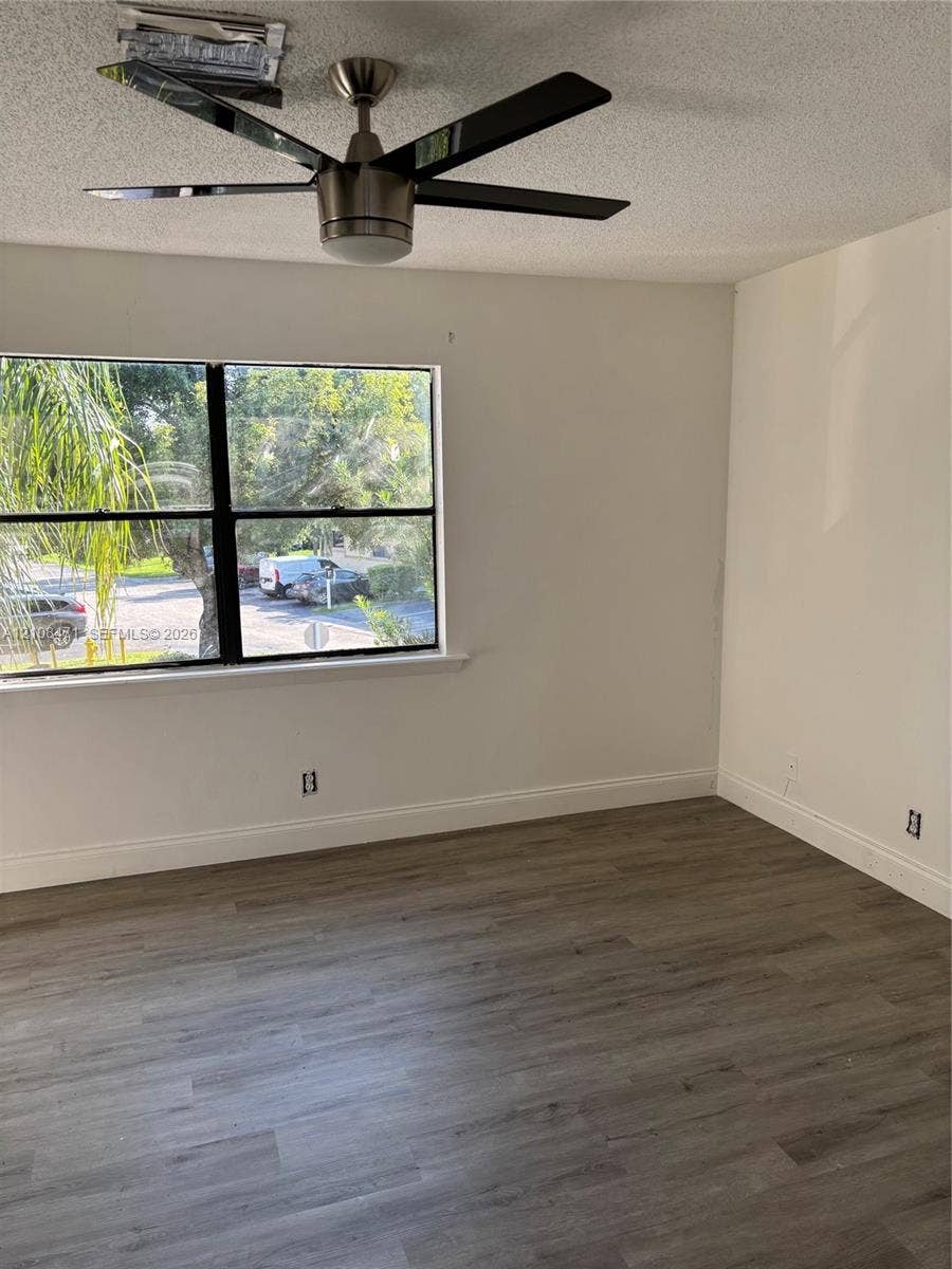 Wood-finish flooring, multi-pane window with black framing, and modern ceiling fan with integrated light fixture